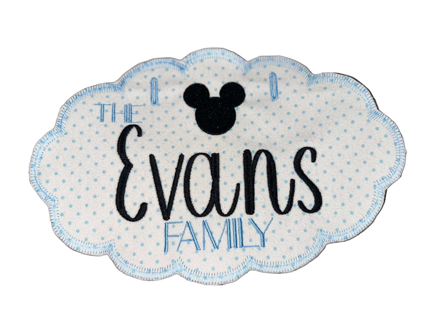 Embroidered patch with 'The Evans Family' text and Mickey Mouse head on a wooden surface